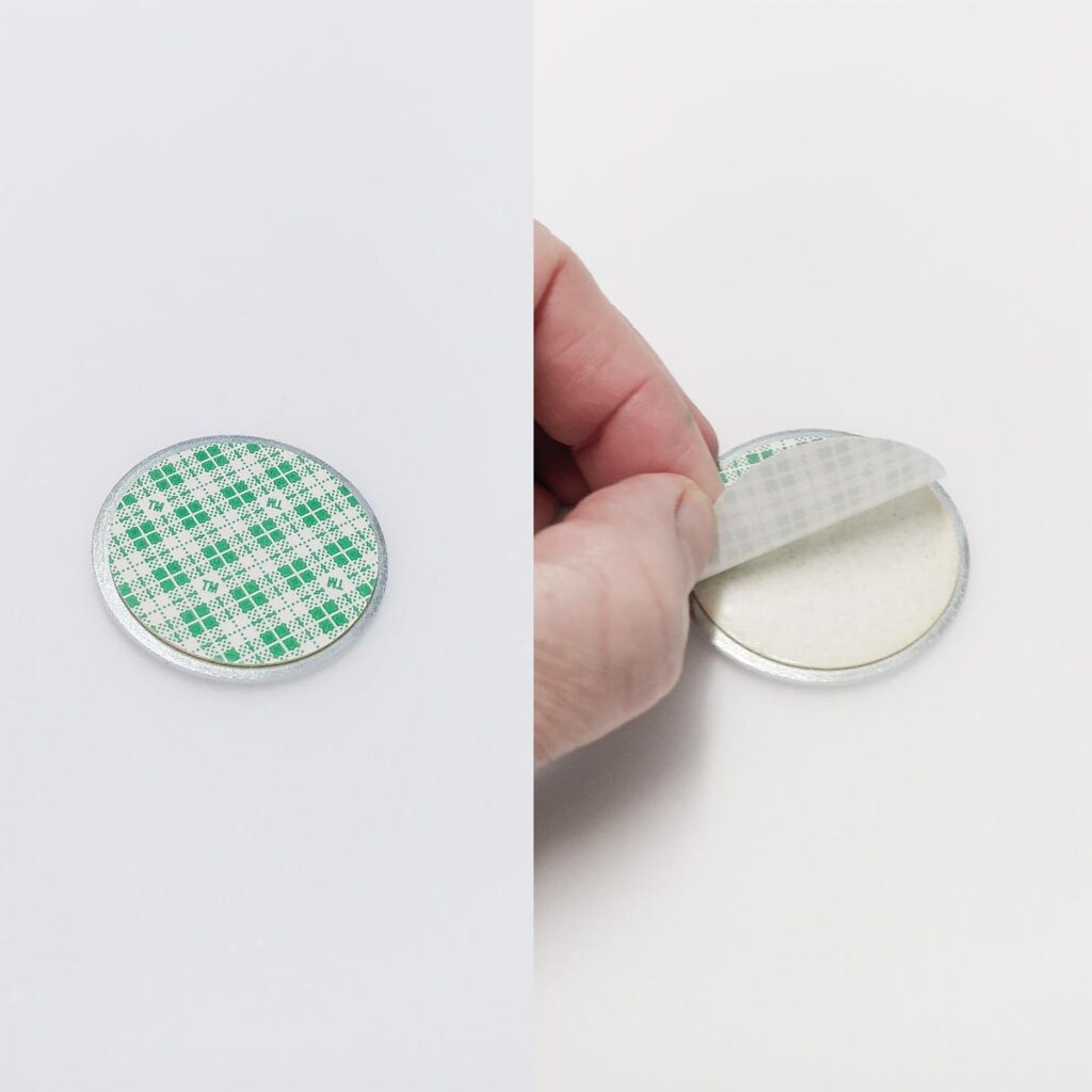 Erklärbild zum Ablösen der Schutzfolie eines selbstklebenden Metallgrundplättchens für Magnete