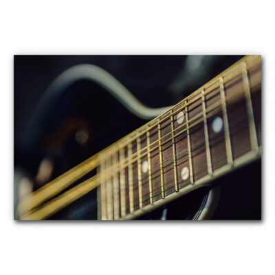 Akustikbild Guitar Strings - Perspektivische Detailaufnahme eines Guitarrenhalses in einer dunklen Stimmung mit goldenen Bundstäbchen und gold-schwarzen Saiten.